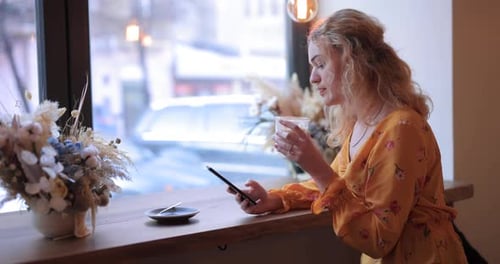 Pretty Woman Using Smart Phone Sitting in a Cafe