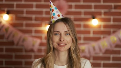 Woman Smiling Wearing Birthday Hat in Festive Room