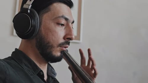 Young Adult Man Plays Cello Wearing Headphones