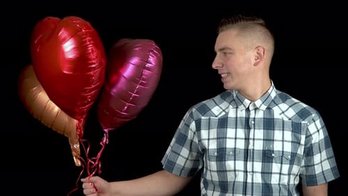 Man Holds Balloons with Heart Shape on Black