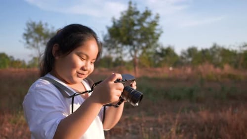 Girl standing in meadow with camera