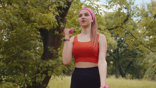 Athletic Young Sporty Fit Girl Doing Dumbbells Workout in Sunny Park Performing Bicep Exercising