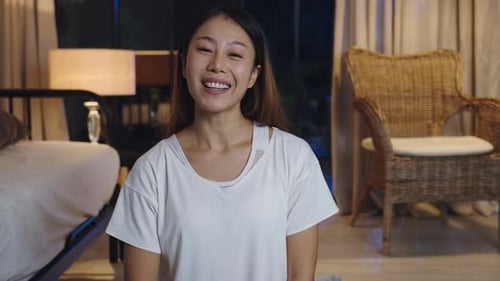 Smiling Woman Waving in Bedroom at Night