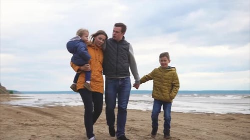 Happy Parents and Two Children Walking on the Coast