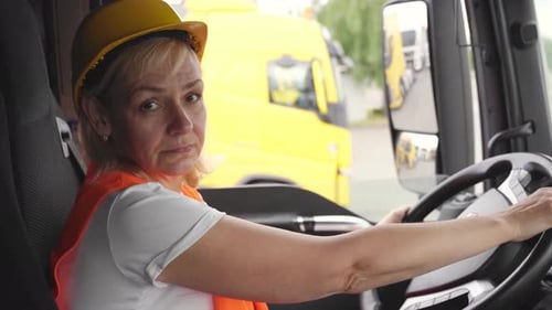 Truck Driver Wearing Hard Hat Smiles in Truck Cab