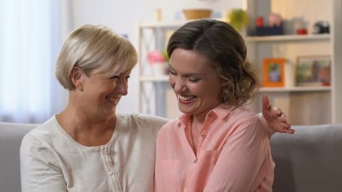 Women Sitting on a Couch and Laughing
