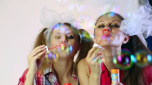 Playful Women Blowing Bubbles with White Hair Bows
