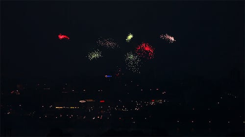 Vibrant Fireworks Exploding Over Dark City Skyline at Night