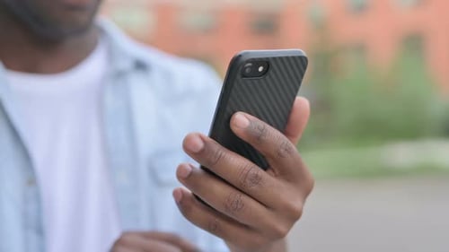 Close Up of Hands of African Man Using Smartphone
