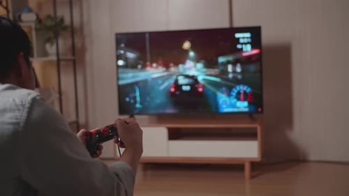 Joven jugador jugando un juego de carreras de coches en la televisión en casa