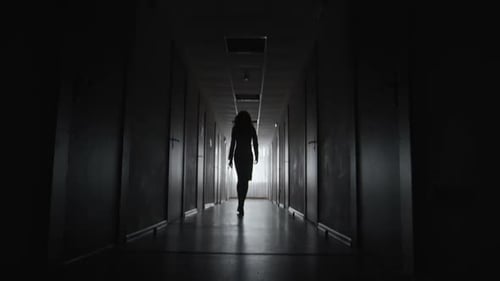 Woman Walking Down a Dark Hallway in Silhouette
