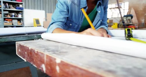 Woman Designs Blueprint in Brightly Lit Workshop