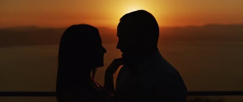 Nahaufnahme eines jungen Paares, das sich bei Sonnenuntergang liebevoll anschaut, lächelnd. Zeitlupe