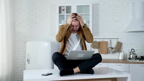 Homme fou utilisant un ordinateur portable assis sur la table à la maison