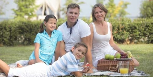Happy Family Enjoying Picnic in Green Field