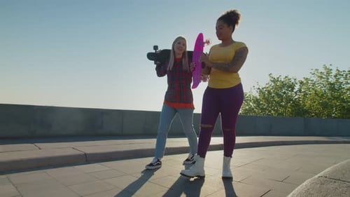 Two Friends Walking and Chatting With Skateboards