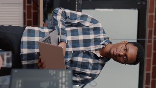 Vertical Video Portrait of African American Software Developer Holding Laptop Looking Up and Smiling