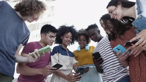 Diverse Young Adults Looking at Cell Phones Together