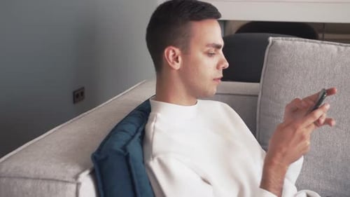 Young Adult Using Smartphone on Couch Indoors