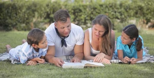 Family Reading Book Together on Lawn