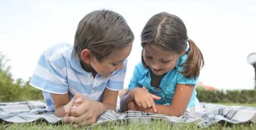 Children Using Tablet Together Outdoors on Blanket