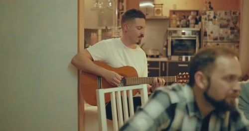 Man Playing Guitar at Home with Friends