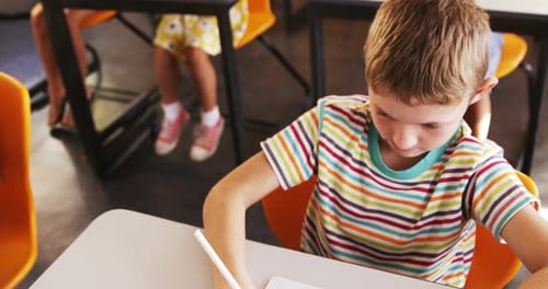 Young Boy Writing at Desk in Classroom