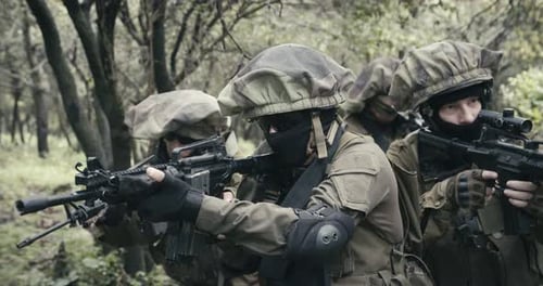 Squad of fully armed commando soldiers during combat in a forest scenery