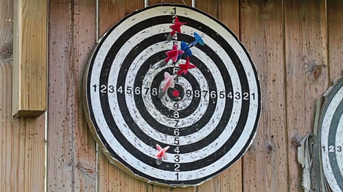 Darts Thrown at Game Dartboard on Wooden Wall