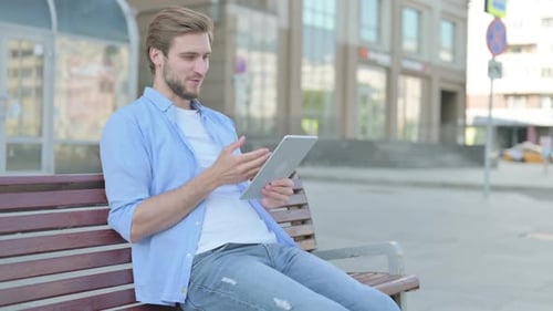 Online Video Chat on Tablet By Man Sitting Outdoor on Bench