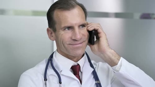 Smiling Doctor Receives Good News on Mobile Phone