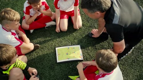 Boys Football Players Are Listening Trainer and Looking on Scheme of Play