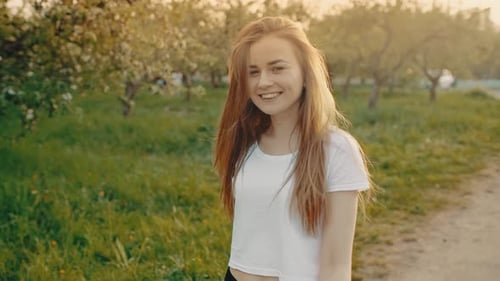 Young Positive Cheerful Girl Walks Outdoors in a Green Natural Park