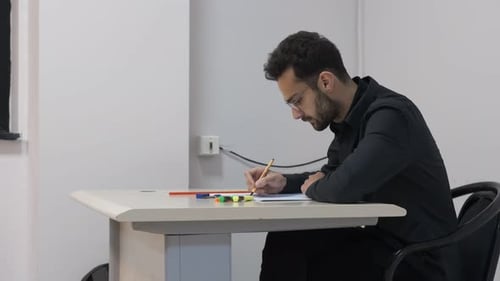 Man Writing at Desk in Classroom Environment