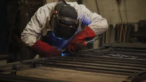 Factory Worker Is Welding Metal in a Workshop of Plant