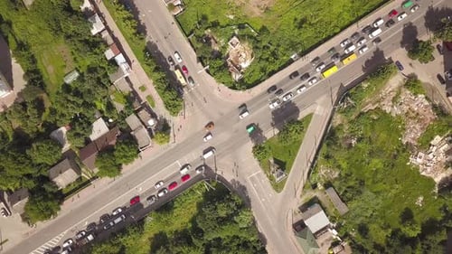Top down aerial view of busy street intersection with moving cars traffic