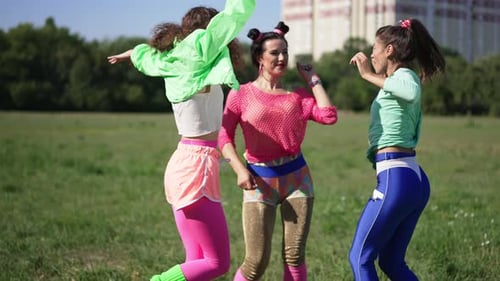 Three Excited Retro Women Having Fun Dancing Jumping in Slow Motion on Sunny Meadow Outdoors