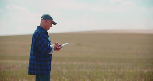Farmer Using Digital Tablet While Examining Field