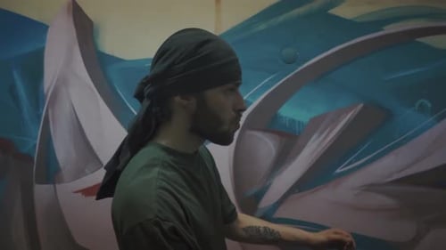 Young Adult Artist Stands Before Graffiti Wall