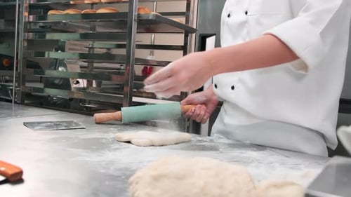 Chef is preparing pastry dough, baking bakery food on a stainless steel table.