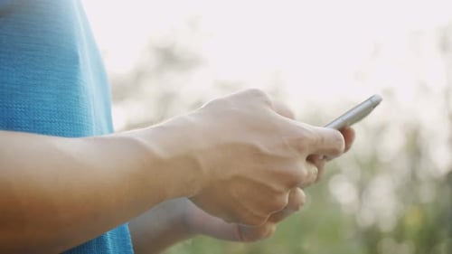 Hands Using Phone Outdoors on Sunny Day