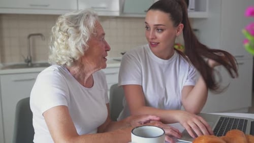 Senior and Young Woman at Kitchen Table with Laptop