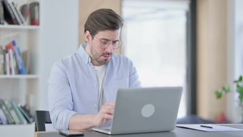 Young Adult Coughing While Working on Laptop