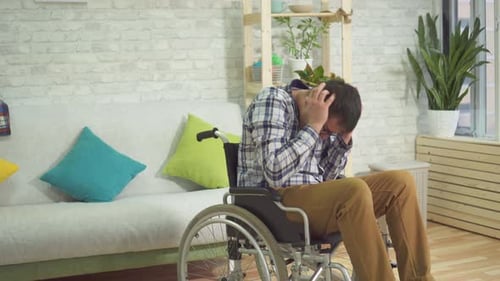 Man in Wheelchair Holds Head in Hands