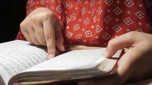 Mão de mulheres muçulmanas lendo o Alcorão à noite