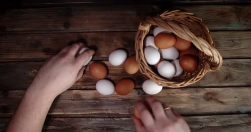 Men's Hands Put Raw Eggs From the Table in the Basket.