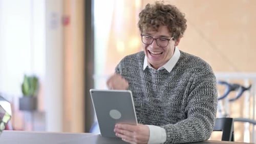 Young Adult Celebrates Success Using Tablet