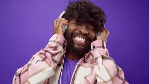 Man Enjoys Music with Headphones on Purple Background