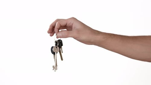 Die Hand eines Mannes auf einem weißen Hintergrund aus Isolat hält die Schlüssel zu einer Wohnung oder einem Auto. Ort zum Einfügen