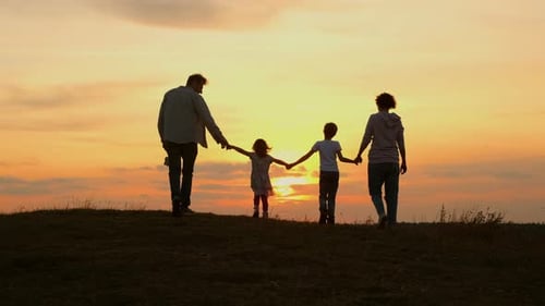 Family Walking on Hilltop at Golden Sunset
